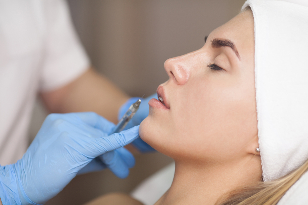 Natural lip enhancement procedure with a specialist carefully injecting filler into a woman's lips.