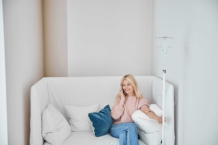NAD IV therapy session with a woman sitting on a couch receiving treatment while talking on the phone