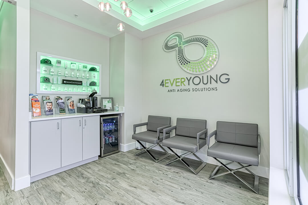 4Ever Young medical spa lobby with grey waiting chairs, a SkinCeuticals product display, and the illuminated 4Ever Young brand logo on the wall.
