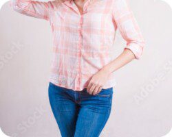 Woman in a fitted pink plaid shirt and jeans posing confidently, showcasing a slim figure achieved through weight loss therapy.