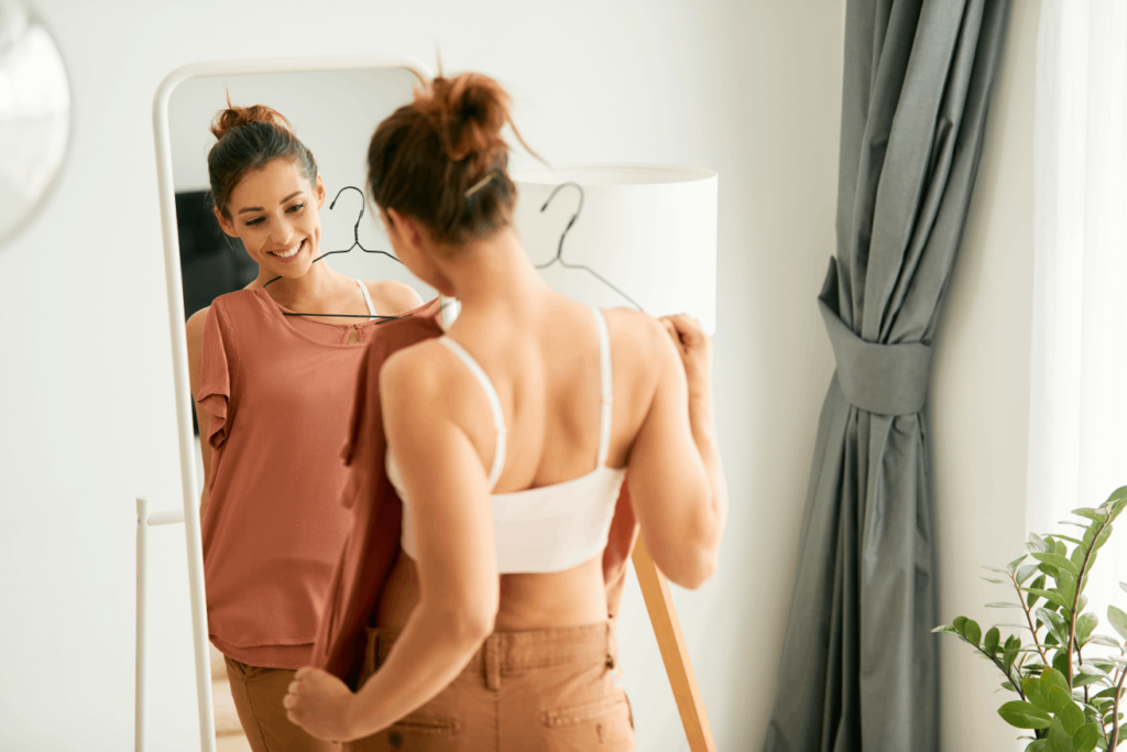 Personalized weight loss program success as a woman smiles while trying on new clothes in front of a mirror.