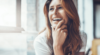 NAD+ IV therapy benefits reflected in a happy woman smiling and relaxing by a bright window.