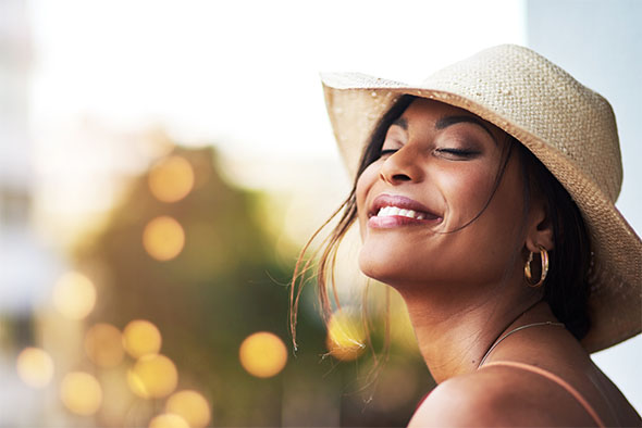 Cosmetic wrinkle treatment shown with smiling woman enjoying youthful, glowing skin in natural sunlight.