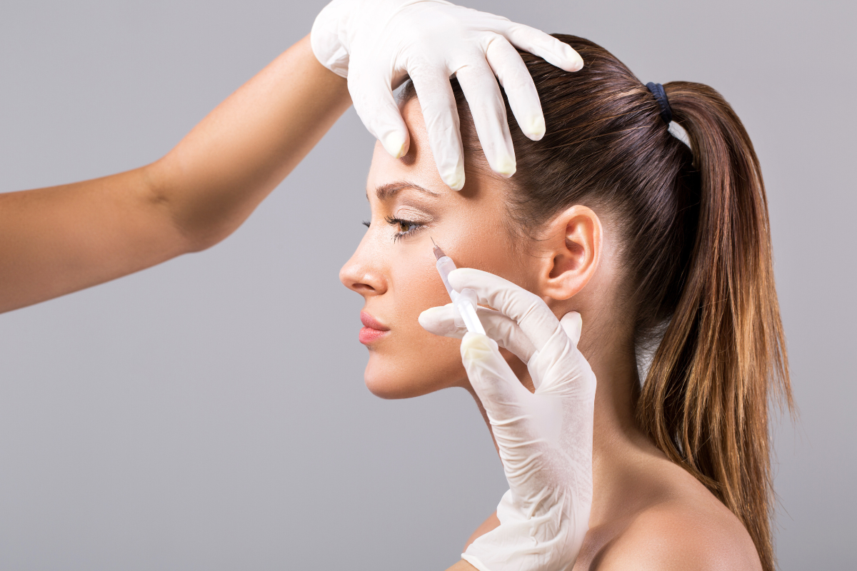 A woman receiving precise facial injections from a gloved specialist during a peptide treatment procedure.