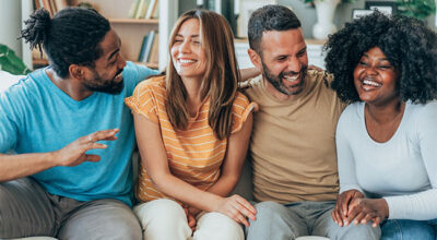 Weight loss clinic success depicted by a joyful group of friends laughing together on a couch.