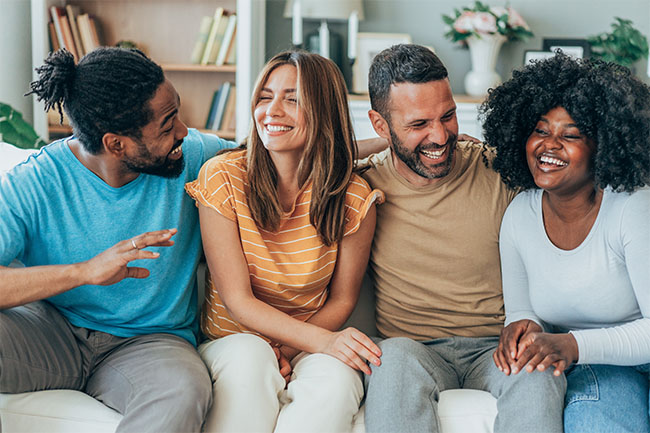 Weight loss clinic success depicted by a joyful group of friends laughing together on a couch.