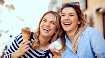 Metabolism-boosting medication results shown by two happy women enjoying ice cream and laughing outdoors.